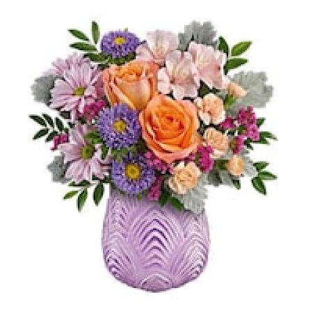 My Lady's Florist Westland - This fun arrangement bursts with springtime energy, beautifully showcased in a sculpted glass vase with a soft lavender hue and frosted finish, evoking the essence of a blossoming garden.