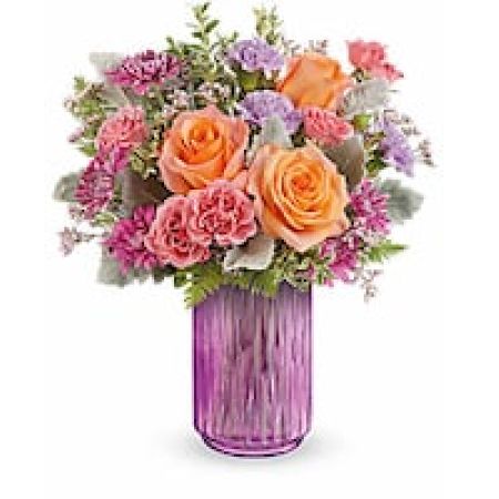 My Lady's Florist Westland - Illuminate their spring dreams with this radiant bouquet, featuring a vibrant mix of orange, pink, and lavender, artfully arranged in a striking pink vase that shines with warmth and cheer.