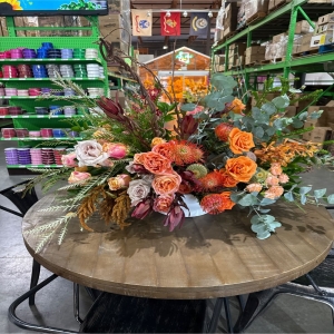 Dottie's Flowers and Plants Los Angeles - Embrace the warm hues of autumn with this stunning, textured floral design—a captivating blend of burnt orange roses, blush pink blooms, and earthy pincushions. Lush eucalyptus foliage adds a fresh, invigorating scent and graceful movement to this eye-catching centerpiece. Perfect for adding a touch of rustic elegance to your home or as a heartfelt **fall flowers** gift for someone special. Send joy and sophisticated style with this unique **flower arrangement** – a beautiful expression of gratitude, sympathy, or simply ‘thinking of you’.