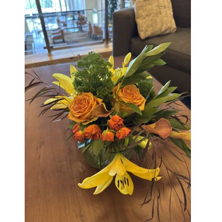 Beaverton Florists- Demo Beaverton - Bring the warmth of autumn indoors with this stunning, hand-tied bouquet of golden lilies and rich peach roses. 
Delicate ferns and textural accents create a captivating centerpiece, radiating cheerful energy and natural beauty. 
Perfect for brightening a room, expressing gratitude, or sending a thoughtful “thinking of you” gift to someone special.
This vibrant floral arrangement is a burst of sunshine, guaranteed to lift spirits and add a touch of elegance to any occasion.