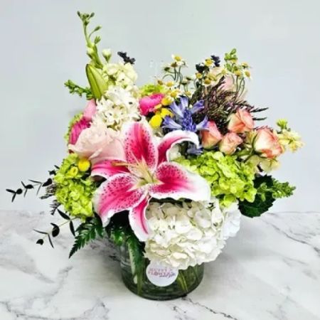 Beaverton Florists- Demo Beaverton - Immerse yourself in the charm of an English garden with this lush floral arrangement. Hydrangeas, Hyacinth, Miniature Tea Roses, and Stargazer Lilies come together in a symphony of elegance within a lavish English garden cylinder vase. Each bloom exudes its unique beauty, creating a captivating display reminiscent of a serene garden oasis.