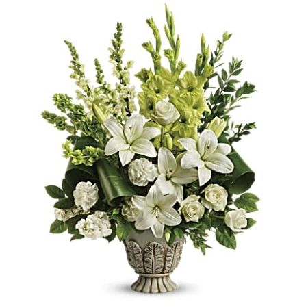 Madison Avenue Florist Sacramento - As serene as gently falling snow, this elegant white arrangement in a large antiqued pot is a heartfelt symbol of peace and beauty, a memory that will remain a guiding light to your loved ones for years to come. White roses, white asiatic lilies, green gladioli, white carnations, bells of ireland, white snapdragons, and white stock are accented with myrtle, green ti leaves, and lemon leaf.
