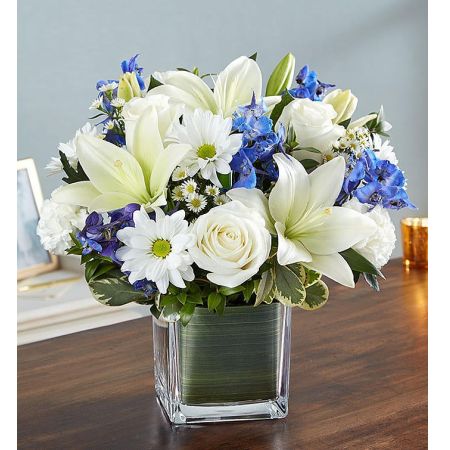 Conroy's Florist & Flower Delivery Mission Viejo - Soothe their tears as they mourn the loss of a loved one with the serenity of blue and white. Our sympathy arrangement of fresh blue delphinium, white roses and lilies, expertly gathered together in a clear glass cube lined with Ti leaf ribbon, makes for an exquisite gesture of comfort and healing.