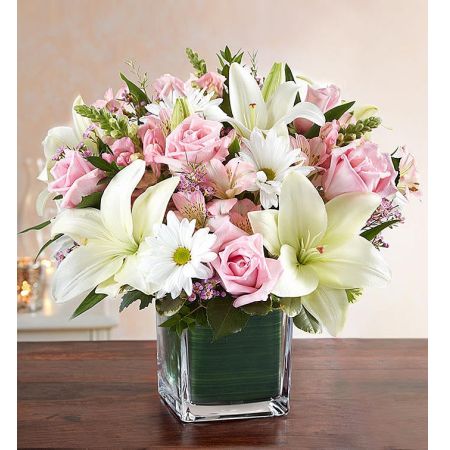 Conroy's Florist & Flower Delivery Mission Viejo - Delicate blooms call to mind beauty, grace and sweetness—a reminder of the dearly departed themselves. Our sympathy arrangement of gentle pink roses and white lilies, expertly gathered in a clear glass cube lined with a Ti leaf ribbon, makes for an exquisite gesture of comfort and healing.