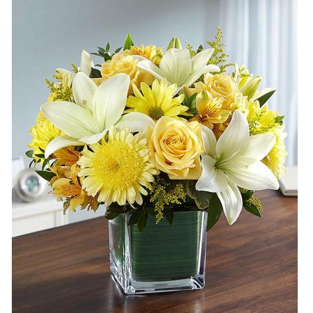 Conroy's Florist & Flower Delivery Mission Viejo - Remind them of a loved one’s sunny disposition with our yellow and white sympathy arrangement.<br/><br/>When sorrow prevails, a tribute in sunny yellow can be a reassurance that brighter days lay ahead. Our sympathy arrangement of bright yellow roses, daisy poms and white lilies, expertly gathered together in a clear glass cube lined with Ti leaf ribbon, makes for an exquisite and uplifting gesture of comfort and healing.