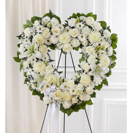 Conroy's Florist & Flower Delivery Mission Viejo - The "Floral Heart Wreath All White" is a beautifully crafted arrangement featuring a delicate composition of white roses, hybrid lilies, football mums, carnations, and daisy poms. Adorned with the elegance of baby's breath and complemented by soft, lush greenery, this wreath exudes a sense of purity and tranquility. Perfect for various occasions, it serves as a heartfelt expression of sympathy, love, or remembrance.