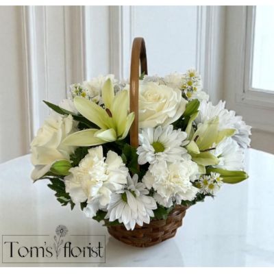 Tom's Florist Smyrna - Honor a beautiful life with the timeless purity of white blooms. The Loving Memory Basket – White is a graceful tribute, thoughtfully presented in a dark handled basket. This all-white arrangement offers a heartfelt expression of peace, remembrance, and love.

Includes:

- White Lilies

- White Daisies

- White Carnations

- White Monte Casino

- White Roses (Deluxe and Premium sizes only)

Whether sent to a service or a loved one’s home, this basket brings comfort and quiet beauty during a difficult time.