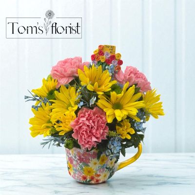 Tom's Florist Smyrna - Brighten someone’s day with Floral Sips, a cheerful burst of color artfully arranged in a charming, floral-designed mug. This petite arrangement features fresh blooms in radiant shades of pink, sunny yellow, and soft blue – a joyful mix that feels like a sip of sunshine.

Perfect for desks, bedside tables, or as a thoughtful “just because” gift, the reusable mug adds an extra touch of whimsy and warmth long after the flowers have faded. Whether you're sending smiles or treating yourself, Floral Sips is a cup full of happiness.