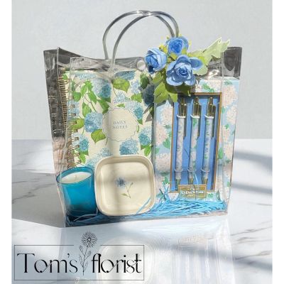 Tom's Florist Smyrna - The Hydrangea Gift Set is a thoughtful blend of beauty, function, and relaxation—perfect for journaling, gifting, or creating peaceful moments throughout the day. Designed with soft florals details, this set brings both elegance and tranquility to any space.

What’s included:

Blue Hydrangea Spiralbound Notebook
Featuring a delicate hydrangea design, this 160-page lined notebook is perfect for journaling, note-taking, or daily inspiration.

Hydrangea 3-Pen Set (Black Ink)
A coordinated trio of smooth-writing pens, each adorned with elegant hydrangea accents to match the notebook.

Small Trinket Dish
A dainty dish for keeping rings, earrings, paperclips, or other small essentials close at hand.

Portfolio Ocean Waves Candle (2.5 oz)
A fresh, calming scent reminiscent of coastal breezes—ideal for setting a relaxing mood at home or at your desk.