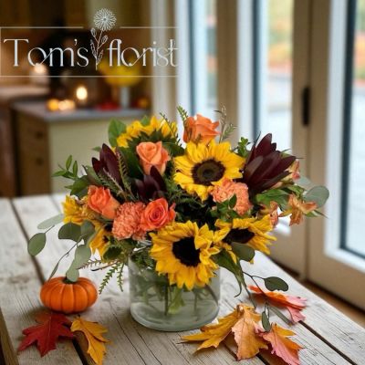 Tom's Florist Smyrna - Capture the glowing hues of a fall evening with Sunflower Sunset — a deluxe arrangement featuring bright sunflowers, vibrant safari sunset, rich orange roses, and cheerful orange carnations. This lively bouquet blends bold yellows and fiery oranges to evoke the magic of a sunset in full bloom.

Perfect for bringing warmth and joy to any room or gifting a splash of seasonal sunshine to someone special.