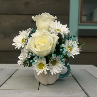 Tom's Florist Smyrna - This charming floral arrangement features delicate white roses and cheerful daisies accented by airy teal baby’s breath
a stunning mix of freshness and tranquility.

Arranged in a chic white mug adorned with teal stripes and a matching handle, it’s the perfect blend of elegance and modern charm.

 Ideal for gifting or brightening your own day.