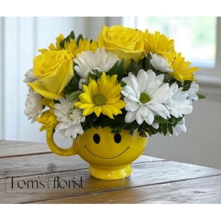 Tom's Florist Smyrna - Bring a burst of joy to someone's day with our Sunshine Smiles Bouquet. This cheerful arrangement features a lovely mix of white and yellow roses and daisies, carefully arranged to brighten any room. Presented in a playful yellow smiley face mug, this delightful floral display is the perfect way to spread happiness and positivity. Whether you're celebrating a special occasion or simply sending a smile, this arrangement is sure to lift spirits and warm hearts.
