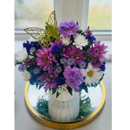 Tom's Florist Smyrna - Indulge in the calming beauty of our Purple Whimsy arrangement, a petite bouquet that exudes elegance and charm. This stunning arrangement features soft lavender carnations, cheerful daisies, delicate statice, and sweet wax flowers in varying shades of purple. A whimsical butterfly pick adds a touch of magic, making this bouquet truly one-of-a-kind.

Perfect for gifting or brightening up your own space, Purple Whimsy is sure to add a serene touch of elegance and wonder to any occasion.
