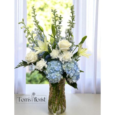Tom's Florist Smyrna - Indulge in the serene beauty of Waterfall Mist, a floral masterpiece that combines the lush elegance of hydrangeas, delphinium, and lilies. This arrangement brings together the soft, voluminous petals of hydrangeas, the delicate elegance of lilies, and the striking beauty of delphinium, creating a harmonious display of nature’s finest offerings.

With its soft yet vibrant colors and varied textures, Waterfall Mist brings a sense of tranquility and refinement to any space. Whether as a thoughtful gift or a beautiful addition to your home, this arrangement captures the essence of natural beauty and timeless elegance, creating a lasting impression with every glance.