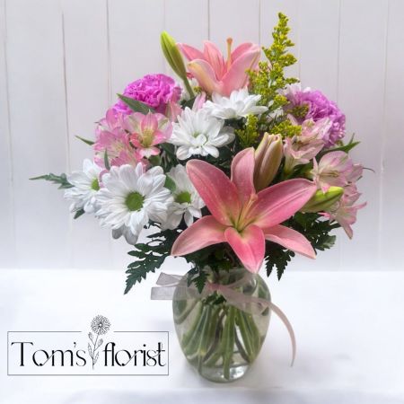 Tom's Florist Smyrna - Soft, sweet, and simply stunning—our Pretty in Pink arrangement is the perfect way to brighten someone’s day! Designed with delicate shades of pink and white, this bouquet is a timeless expression of love, appreciation, and joy.

Available in Three Stunning Sizes:
✔ Standard – A sweet blend of daisies, carnations, and pink lilies for a fresh and classic look.
✔ Deluxe – An elevated version replacing carnations with roses for added elegance.
✔ Premium – The ultimate display of beauty with pink lilies, roses, carnations, and white daisies, creating a lush and luxurious bouquet.

Whether celebrating a birthday, sending love, or just because, this bouquet is a timeless expression of grace and beauty.
