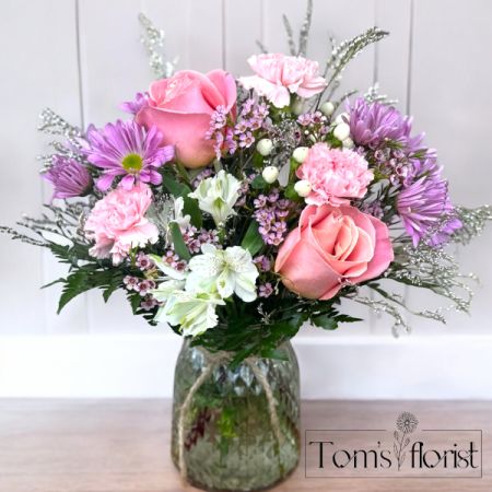 Tom's Florist Smyrna - Soft, sweet, and effortlessly charming — Pretty as a Petal is a delicate mix of blush pink, lavender, and creamy white blooms arranged to perfection in a diamond-cut glass vase, finished with a natural twine accent for a touch of rustic elegance.

This one-sided bouquet features a thoughtfully layered blend of roses, alstroemeria, carnations, daisies, wax flower, and limonium — each bloom chosen for its gentle color and timeless beauty. It’s a light and lovely gesture, ideal for birthdays, new beginnings, or simply brightening someone’s day.
