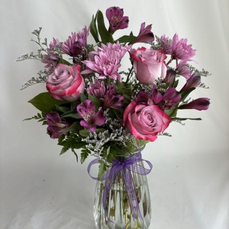 Conroy's Flowers San Diego San Diego - A graceful medley of blush roses, soft lavender blooms, and delicate purple accents, artfully gathered in a clear glass vase with a sheer ribbon finish. Refined and romantic, this arrangement evokes quiet elegance with a touch of modern luxury.