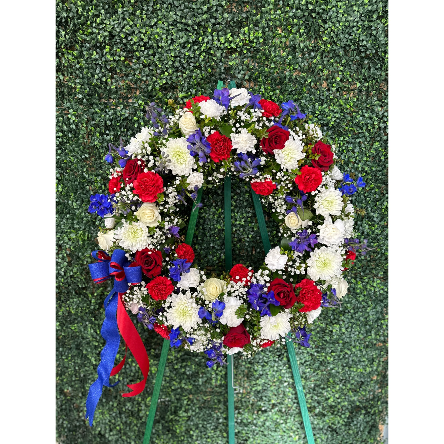 Conroy's Flowers El Cajon El Cajon - In tribute to those who served their country with honor and pride, our Serene Blessings™ Standing Wreath- Red, White & Blue stands as a beautiful symbol of eternal life. Meticulously crafted by our skilled florists, this patriotic standing wreath is a fitting and respectful homage to a brave veteran who has passed away. The arrangement is filled with lush blooms in red, white, and blue hues, creating a poignant and dignified final tribute for the funeral services.