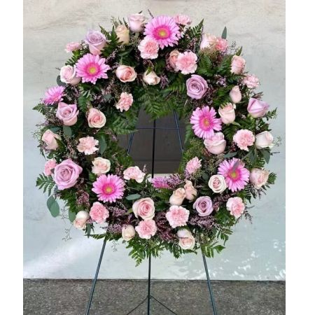 Morningside Florist Rancho Cordova - 4 inch Pink Easel Wreath, created with love by Toya.   Sending this 24-inch pink easel wreath is a beautiful way to express heartfelt emotions, be it for a solemn occasion or a celebration of life. The wreath, with its soft pink roses that symbolize grace and admiration, and the vibrant pink gerbera daisies representing innocence and purity, weaves a tapestry of gentle affection. The varied tones of pink are complemented by delicate spray carnations and accentuated with hints of deeper pink hues from the heather, creating a visual harmony that is both soothing and uplifting. Set against lush green foliage, this wreath not only signifies love and sympathy but also celebrates the beauty of life with its elegant and loving embrace. Perfect for anniversaries, commemorations, or as a respectful tribute, this pink easel wreath stands as a testament to tenderness and cherished memories.