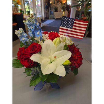 Morningside Florist Rancho Cordova - A heartfelt patriotic arrangement designed to honor, remember, and celebrate with grace.

A lush blend of red roses, white lilies, red gerbera daisies, and blue delphinium comes together in a striking red‑white‑and‑blue palette. The blooms are arranged in a natural, garden‑inspired style, with soft greenery adding fullness and gentle movement. An American flag rises above the flowers, creating a meaningful focal point that symbolizes honor and remembrance.

Perfect for America's 250th Birthday celebration, BBQ's, Memorial Day, Veterans Day, military services, celebrations of life, or any moment when a patriotic tribute feels right.