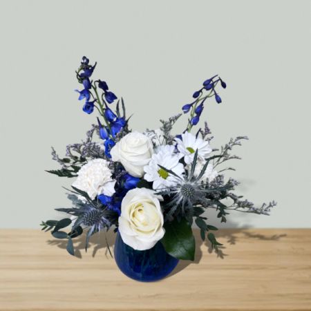 Blooms of Wayne Wayne - Let ‘Rhapsody in Blue’ compose a moment of serene beauty, with its cool tones of delphinium and thistle dancing around creamy white roses and daisies. This stunning arrangement, presented in a rich cobalt vase, evokes a sense of peaceful sophistication for any space. Send this exquisite blue flower bouquet to express heartfelt sympathy, admiration, or simply to brighten someone’s day with a touch of elegant calm. A captivating blend of texture and color, it’s a gift they’ll truly cherish – perfect for flower delivery and creating lasting memories. Inclydes a keepsake vase.