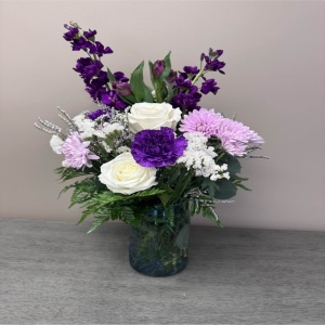 Blooms of Wayne Wayne - Bring a burst of joyful color into someone’s day – or your own! ‘Perky Purple’ is a delightfully charming arrangement designed to uplift spirits and express affection. Imagine a cascade of lavender and violet hues radiating a calming yet cheerful energy. This beautiful bouquet features lush blooms that feel as soft as velvet evoking the sweet scent of a spring garden. It’s a perfect gift for birthdays thank you gestures or simply to show you care. The arrangement’s compact size makes it ideal for a desk bedside table or as a welcoming centerpiece. Let ‘Perky Purple’ deliver a little moment of happiness with its timeless beauty and fragrance.  A truly lovely expression of thoughtfulness this bouquet creates an instant feeling of warmth and serenity.