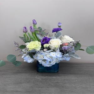 Blooms of Wayne Wayne - Evoke the carefree spirit of a sun-drenched beach day with 'Take Me Down The Shore.' This captivating arrangement is a vibrant medley of textures and hues reminiscent of seashells, sea glass and the gentle ocean breeze. Soft white roses unfurl alongside delicate blue hydrangeas creating a feeling of serene tranquility. Accents of lavender lisianthus add playful pops of color mirroring the joy of salty air and warm sunshine.  Whether you’re seeking to brighten a coastal home, express heartfelt sympathy or simply celebrate life's little moments this bouquet captures the essence of seaside bliss.  Send a wave of happiness to someone special or treat yourself to a piece of paradise. This stunning flower arrangement is perfect for birthdays, get well wishes or to say ‘just because’.