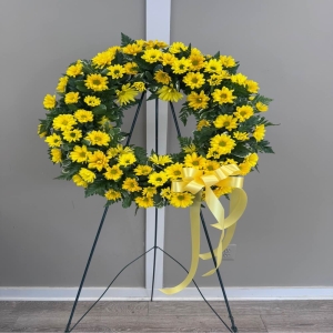 Blooms of Wayne Wayne - Send sunshine and enduring sympathy with our Yellow Daisy Tribute Wreath. This radiant circle of blooms offers a warm and comforting embrace during times of loss. Masses of cheerful yellow daisies evoking feelings of hope and remembrance are skillfully arranged to create a visually stunning and heartfelt expression of care. The natural green foliage provides a beautiful contrast enhancing the vibrant hues of the daisies. More than just a beautiful arrangement this wreath is a tribute to a life well-lived a symbol of lasting affection and a gentle way to say 'We are thinking of you'. Perfect for memorial services graveside tributes or expressing condolences to a grieving family. Its bright and uplifting presence provides solace and acknowledges the beauty that remains in cherished memories. Deliver a message of peace and support with this exquisite floral wreath.