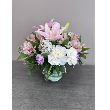 Blooms of Wayne Wayne - Send a moment of pure grace with 'A Simple Gesture'. This beautifully curated arrangement speaks volumes without saying a word. Soft blush-toned roses unfurl alongside delicate lilies creating a haven of tranquility and gentle fragrance. The sprigs of alstroemeria add a playful touch while the lush greenery provides a grounding balance. Imagine this bouquet brightening a loved one’s day offering comfort during a difficult time or simply celebrating the small joys in life. It's the perfect way to show you care express sympathy or offer a heartfelt ‘thank you’. A truly elegant and understated display of affection ideal for any occasion. Enjoy the soothing beauty and lasting freshness of this exquisite floral gift.