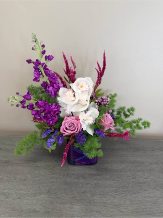 Blooms of Wayne Wayne - Indulge in the timeless beauty of 'Rose and Orchid Romance' a breathtaking arrangement designed to stir the heart. Imagine the delicate fragrance filling a room, a soft whisper of love and admiration. This exquisite bouquet features lush roses in varying shades unfolding with graceful elegance alongside the exotic allure of premium orchids. The interplay of textures – the velvety petals of the roses contrasted with the smooth sculptural forms of the orchids – creates a visual masterpiece. It’s more than just flowers; it’s an expression of deep affection perfect for anniversaries celebrations or simply to show someone you care. Bring a touch of sophisticated romance into their life with this stunning blend of nature’s most cherished blooms. This arrangement is expertly crafted to last ensuring long-lasting enjoyment.
