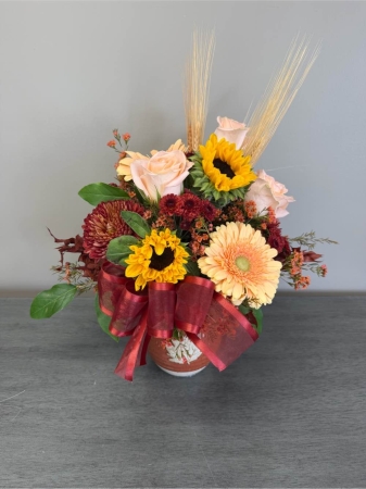 Blooms of Wayne Wayne - Bring a burst of sunshine and effortless charm into any space with 'Pitcher This'. This delightful arrangement presented in a classic ceramic pitcher overflows with the natural beauty of freshly cut blooms. Imagine the soft light catching the delicate petals filling the room with a gentle fragrance – a touch of the garden indoors. It's more than just flowers; it’s a feeling of relaxed joy perfect for brightening a kitchen table, welcoming someone home or simply treating yourself to a little everyday luxury. 'Pitcher This' makes a thoughtful gift for any occasion radiating warmth and a heartfelt sentiment.