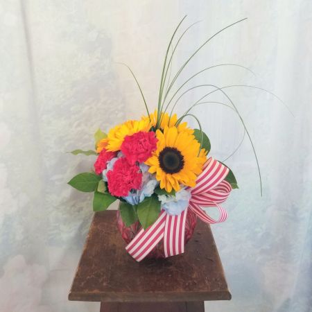 Log Cabin Florist Bakersfield - Cute little bouquet in bright colors of carnations, gerbera daisies, sunflowers and hydrangea in a colored etched bubble bowl finished with a striped bow. Approx. 10"H x 9"W. ***Colors of flowers and vase may vary***