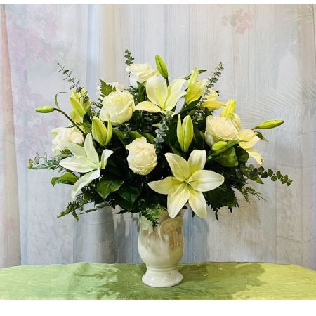 Log Cabin Florist Bakersfield - Celebrate a wonderful life with this timeless tribute of pure white lilies and roses, arranged in a graceful tulip-shaped ceramic vase.
This monochromatic bouquet features crème roses, white lilies, spiral eucalyptus, and lemon leaf.