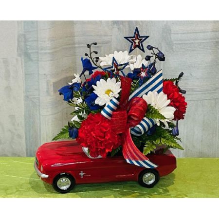 Log Cabin Florist Bakersfield - Featuring our Patriotic Red Mustang with red carnations, white daisy poms, blue delphinium, stars decor and striped ribbon. Approx. 10"H x 9"W***Flowers, container, decor and ribbon may vary depending upon availability***