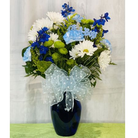 Log Cabin Florist Bakersfield - Welcome the new baby boy with this adorable bouquet! A mix of daisy poms, button poms, blue carnations, delphinium, and solidago is arranged in a charming blue vase. Standing at approximately 18 inches in height and 13 inches in width, this bouquet adds a delightful touch to the celebration. Please note that flower selection may be subject to change based on availability, ensuring the freshest and most charming arrangement possible. Enjoy the convenience of same-day flower delivery to share your warm wishes for the newest addition to the family.