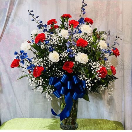 Log Cabin Florist Bakersfield - Beautiful sympathy arrangement for the home of red and white carnations with blue delphinium and baby's breath in a glass vase with a blue bow. Approx. 38"H x 28"W ***Flowers and container may be substituted depending upon availability*** 