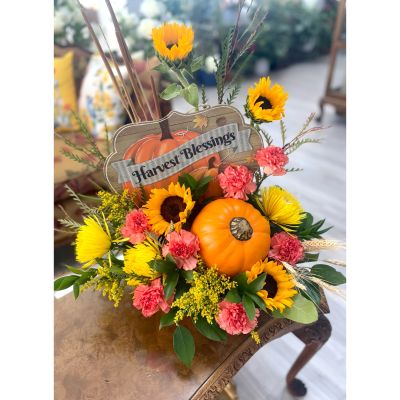 DiBella Flowers & Gifts Las Vegas - Celebrate the season with this cheerful fall centerpiece bursting with warmth and charm. Featuring bright sunflowers, golden mums, and coral carnations accented with lush greenery and wheat, this arrangement captures the beauty of autumn harvest. A festive pumpkin and rustic “Harvest Blessings” sign complete the look, making it the perfect decoration for your home, holiday table, or as a thoughtful gift.