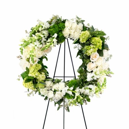 DiBella Flowers & Gifts Las Vegas - Heartfelt and commemorative, this striking circular wreath showcases lovely blooms, in shades of white and green, cascading from a base of verdant seasonal greenery. This wreath comes displayed on an easel, making it a beautiful backdrop for any service. Medium size pictured here.

Medium (as shown) is approximately 21" in diameter

<i>This arrangement is custom designed using best-of-day seasonal flowers and may not feature the exact flowers shown. If an item is unavailable, we’ll substitute in products of equal or greater value. Please call us at 702-384-1121 to inquire about our flower selection before placing your order if you require specific flowers be included.</i>