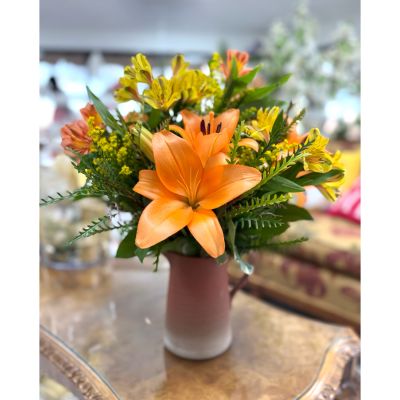 DiBella Flowers & Gifts Las Vegas - This charming fall arrangement features vibrant orange lilies accented with golden-yellow blooms and soft, textured greenery, all gathered in a rustic, two-tone ceramic pitcher. The warm autumn palette brings a cozy, welcoming feel, making it an ideal centerpiece for Thanksgiving gatherings or seasonal décor. The soft gradients of the pitcher add an artisanal touch that complements the natural beauty of the flowers. Perfect for brightening a dining table, entryway, or living room, this arrangement captures the essence of harvest-season warmth.