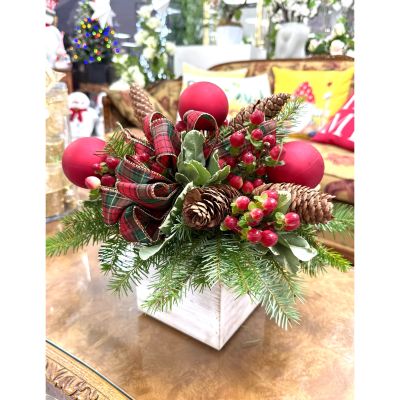DiBella Flowers & Gifts Las Vegas - This festive holiday arrangement "Merry In the Woods" features a charming blend of natural and decorative elements. It includes evergreen branches, pinecones, red berries, and a red ornament ball, all complemented by plaid ribbon accents. Set in a rustic white wooden container, this arrangement exudes a cozy, traditional holiday feel—perfect for a Christmas centerpiece or seasonal décor.