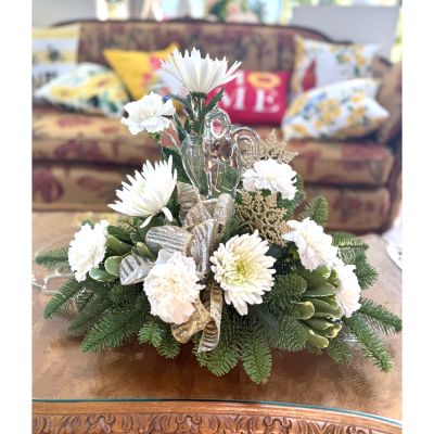 DiBella Flowers & Gifts Las Vegas - A lush holiday arrangement featuring a stunning angel figurine, fresh evergreens, elegant white blooms, and shimmering silver accents. Soft carnations and chrysanthemums are beautifully layered with seasonal greenery, while metallic ribbons and a sparkling ornament add a touch of winter magic. Perfect as a festive centerpiece or a sophisticated gift, this design brings a crisp, classic holiday feel to any home.