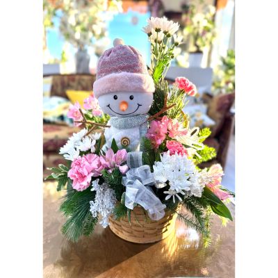 DiBella Flowers & Gifts Las Vegas - Frosted Pink Wishes is a charming winter arrangement featuring a sweet snowman figure nestled among soft pink blooms, crisp white flowers, and fresh seasonal evergreens. Arranged in a natural woven basket, this design blends playful holiday cheer with gentle pastel elegance. Sparkling silver accents and delicate textures add a frosty touch, making it a perfect gift for spreading joy, warmth, and festive beauty all season long.