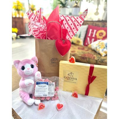 DiBella Flowers & Gifts Las Vegas - Sweet, cozy, and made for sharing, the Date Night Bag is the perfect Valentine’s Day treat wrapped up in pure charm. This thoughtfully curated goodie bag comes beautifully presented in a classic kraft bag, topped with playful Valentine’s tissue paper bursting with hearts and festive flair. A soft red heart tag adds the perfect finishing touch, making it feel extra special from the moment it’s seen.

Inside, you’ll find an irresistibly cuddly pink kitty stuffed animal, full of personality and sweetness—perfect for snuggling or as a keepsake long after the treats are gone. Nestled alongside is a bag of Family Choice candies, offering a nostalgic mix of sweets to share, snack on, or enjoy during a movie night in. Completing the experience is a luxurious Godiva assorted chocolate box, tied with an elegant ribbon and filled with rich, indulgent chocolates that turn any evening into something memorable.

Whether it’s for a romantic night in, a first date surprise, or a heartfelt gift for someone you adore, the Date Night Bag brings together sweetness, comfort, and a little bit of indulgence—all wrapped up in one charming Valentine’s package. 