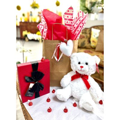 DiBella Flowers & Gifts Las Vegas - When love calls for a last-minute save or a perfectly timed surprise, the Emergency Valentine Rescue Bag comes to the rescue in the sweetest way possible. This charming Valentine’s goodie bag is beautifully styled in a classic kraft paper bag, filled to the brim with festive red and heart-patterned Valentine’s tissue paper that pops with romance and playful charm. A soft fabric heart tag tied with coordinating ribbon hangs from the handle, adding a heartfelt, keepsake-worthy detail.

Inside this love-ready bag is a cuddly white stuffed bear, irresistibly soft and full of warmth, featuring an adorable red bow tie that gives it a polished, love-struck look. It’s the kind of plush companion that instantly melts hearts and begs to be hugged. Paired perfectly with the bear is a decadent truffle chocolate box, wrapped in rich red packaging and finished with an elegant bow—packed with indulgent chocolates that make any Valentine’s moment feel extra special.