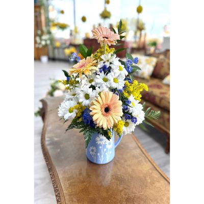 DiBella Flowers & Gifts Las Vegas - Pitcher Perfect is the sweetest blend of charm and cheer. Designed in an adorable light blue pitcher adorned with delicate white daisies, this arrangement feels like a breath of fresh countryside air. Soft peach gerbera daisies take center stage, beautifully complemented by crisp white daisies, vibrant pops of yellow solidago, and touches of rich blue blooms for the perfect hint of contrast.