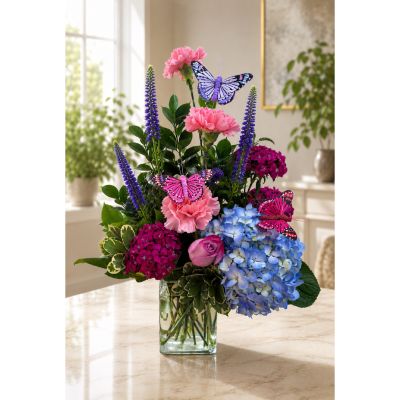DiBella Flowers & Gifts Las Vegas - Created in loving remembrance of Dolly Parton, the 9 to 5 Collection: Love Is Like a Butterfly celebrates her colorful spirit, timeless music, and joyful legacy. Pink and blue blooms are accented with vibrant butterflies, creating a heartfelt floral tribute for fans who will always cherish the Queen of Country. Available from DiBella Flowers and Gifts with same-day flower delivery in Las Vegas when available.