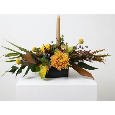 Uptown Blossoms  - Bring the warmth of autumn indoors with our Harvest Holiday Centerpiece, a stunning blend of rich textures and earthy tones. 
Deep burgundy berries, blush roses, and golden mums are artfully arranged around a graceful ivory candle, creating a soft, inviting glow. 
The fragrance is subtle and comforting – a perfect tabletop accent for Thanksgiving gatherings or a heartfelt gift to express your gratitude. 
This beautiful fall floral arrangement adds a touch of seasonal elegance to any home, embodying the spirit of the harvest season.