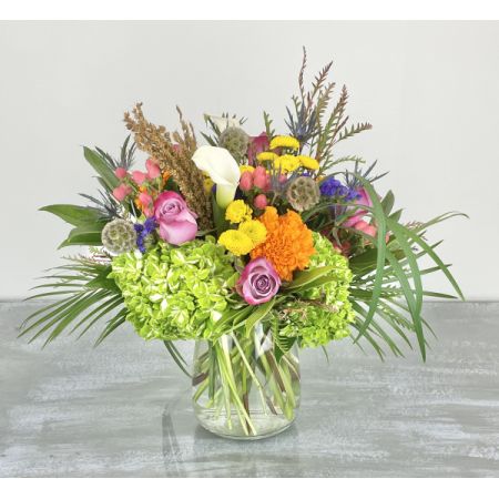 Hilly Fields Florist  Tallahassee - A wild and beautiful arrangement inspired by the lush landscapes of Kerry, Ireland. 'The Kerry Forest' bursts with a vibrant mix of textures and colours – soft lavender roses, elegant white calla lilies, cheerful yellow and orange blooms, and a touch of whimsical thistle. Green hydrangeas and unique foliage create a full, natural look, delivered in a classic glass vase. It’s a captivating piece that brings the outdoors in, perfect for a statement gift or to brighten your own home.***Arrangements are created to order and may not look exactly as pictured based on seasonal availability. Our designers will take care to ensure they maintain the colors, shapes and textures of the arrangement if substitutions are necessary.***