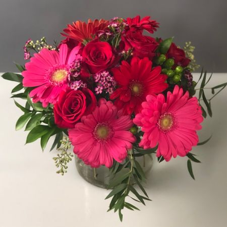Bouquets Denver - Simple and classic Gerbera Daisies with roses and complimentary flowers. Beautiful lush euromass in clear glass vase. COLORS WILL VARY depending on market availability.